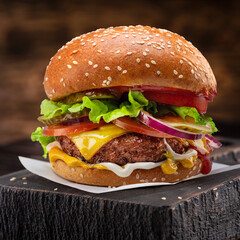 Tasty cheeseburger on wooden tray close-up.