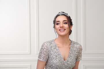 Beautiful young woman wearing luxurious tiara indoors, space for text