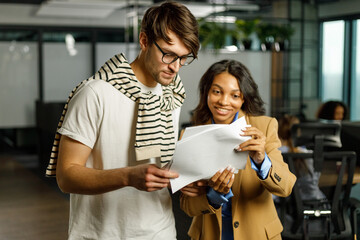 Happy black woman assistant with senior man CEO showing documents for market research idea