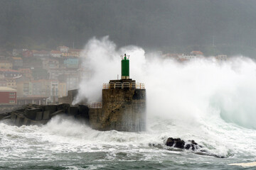 Fototapeta na wymiar Olas enormes rompiendo en el faro del puerto de A Guarda. Pontevedra, Galicia, España.
