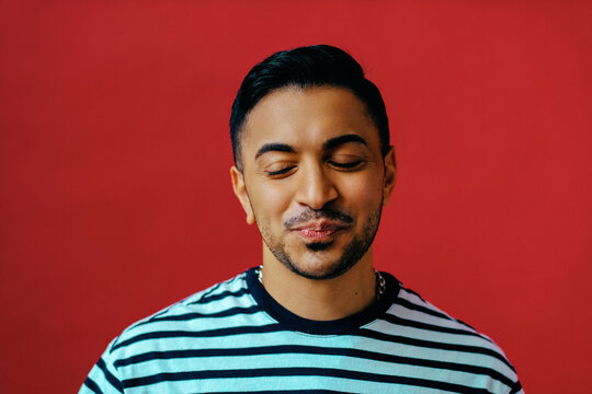Non-binary person with eyes closed in studio portrait