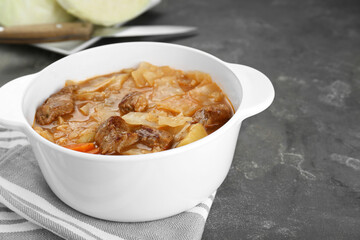 Tasty cabbage soup with meat and carrot on grey table, closeup. Space for text