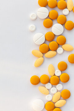 Orange and white medical tablets scattered on white with copy space