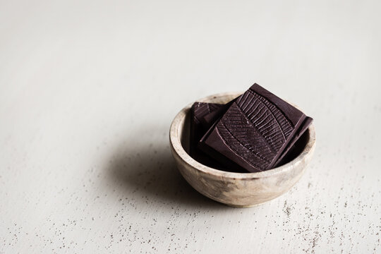 dark chocolate pieces in a small wooden bowl