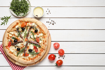 Tasty pizza with anchovies and ingredients on white wooden table, flat lay. Space for text