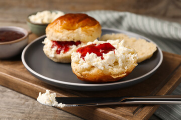 Freshly baked soda water scones with cranberry jam and butter on wooden table, closeup