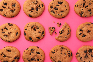 Many delicious chocolate chip cookies on pink background, flat lay