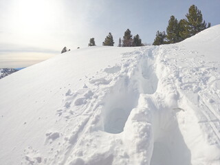 Fototapeta na wymiar Footprints in deep snow going up. Backcountry trail. Winter hike