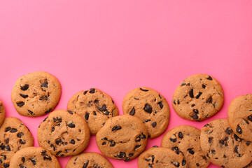 Many delicious chocolate chip cookies on pink background, flat lay. Space for text