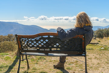 Woman sitting admiring the scenery on a clear day with clouds on the horizon.