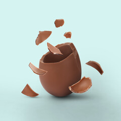 Exploded milk chocolate egg on dusty light blue background