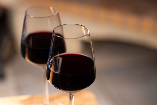 deux verres de vin rouge posés sur une table avec en arrière plan un feu de cheminée. Reflet des verres sur la table. Concept de la convivialité à l'heure de l'apéritif