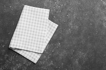 Beige checkered tablecloth on black textured table, top view. Space for text