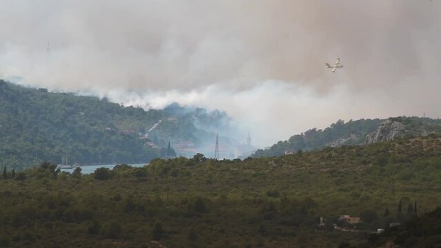Firefighting amphibious aircraft Canadair Bombardier CL-415 flies over the town of Zaton, Croatia and dumps water to extinguish fire. Firefighting, aviation, natural disasters and environment concepts