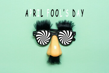 funny face - fake eyeglasses, nose and mustache, calendar date 01 April on green background Happy...