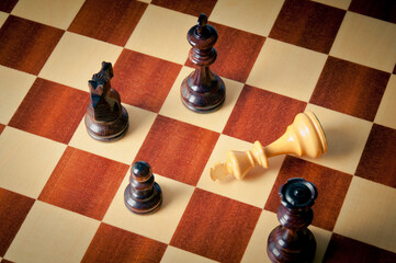 chess pieces on the chessboard and king down, checkmate concept