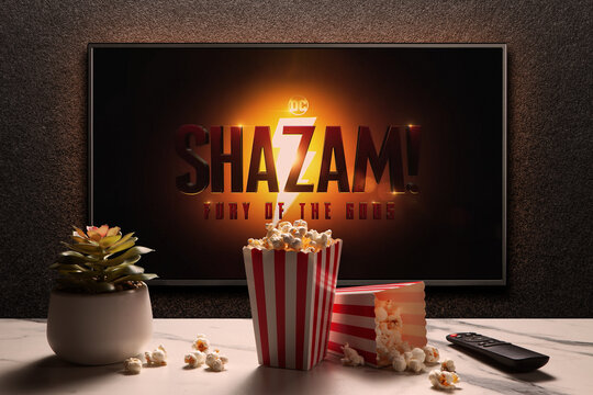 TV screen playing Shazam Fury of the Gods trailer or movie. TV with remote control, popcorn boxes and home plant. Moscow, Russia - March 14, 2023.