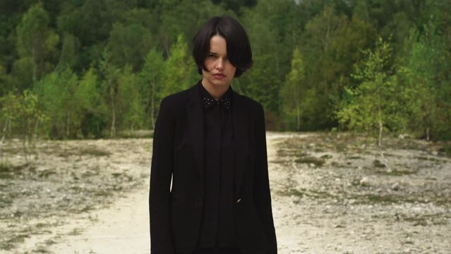 Portrait shot of a scared caucasian woman in a black suit in a forest