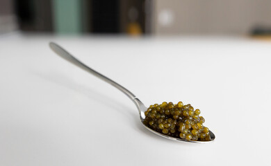 a levitating teaspoon with black sturgeon caviar on the table