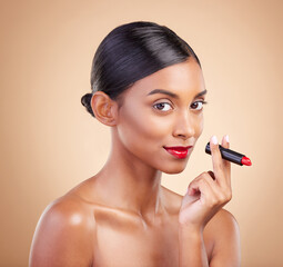 Portrait, skincare and Indian woman with lipstick, beauty and happy against brown studio...