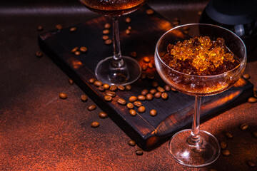 Espresso coffee slush cocktail in martini glass, with craft drips coffee maker. Hard coffee granita, on dark brown background copy space