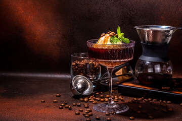 Fototapeta na wymiar Irish coffee affogato, Espresso martini cocktail with ice cream ball and caramel topping, on dark brown background copy space