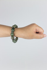 Hand with jade beads isolated on white background. Studio shot.