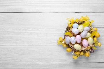 Festively decorated Easter eggs on white wooden table, top view. Space for text
