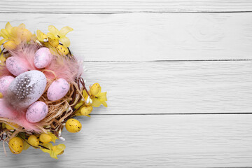 Festively decorated Easter eggs on white wooden table, top view. Space for text