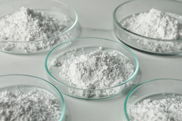 Petri dishes with calcium carbonate powder on white marble table, closeup