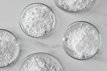 Many petri dishes with calcium carbonate powder on white marble table, flat lay