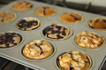 Close-up of fresh homemade blueberry muffins with sliced almonds in a baking tray with selective focus. Sweet cakes, baked goods concept.