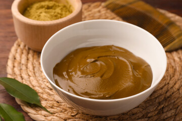 Bowl of henna cream on wooden table, closeup. Natural hair coloring