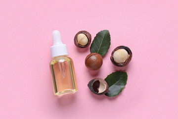 Delicious organic Macadamia nuts, natural oil and green leaves on pink background, flat lay