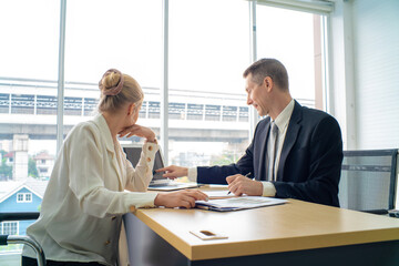 Professional business boss talking with secretary in modern office with waindow