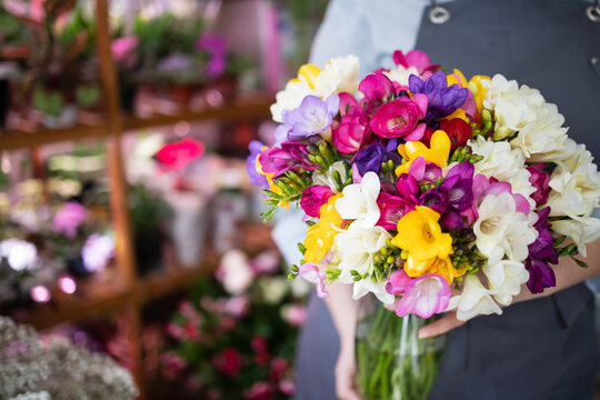 Female florist has no face holding a vase of freesias in a flower shop. Spring flowers, delicate, sophisticated, flower delivery, mothers day, valentines day, sale, advertising, copy place, mockup