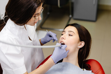 Teeth health concept. Attractive girl opening mouth under treatment at dental clinic and dentist...