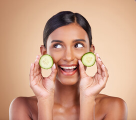 Woman, thinking and cucumber for natural skincare, beauty and nutrition cosmetics against a studio background. Happy female holding vegetables in thought for healthy organic diet or facial treatment