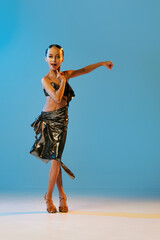 Expressive dance. Beautiful little girl in stage attire dancing latino madern ballroom dance over...