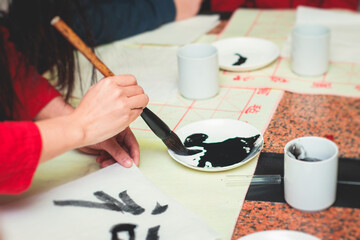 Chinese calligraphy lesson, group of kids learn and practicing traditional calligraphy in class,...