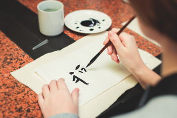 Chinese calligraphy lesson, group of kids learn and practicing traditional calligraphy in class, kid black with ink and brush learn writing of chinese characters in school