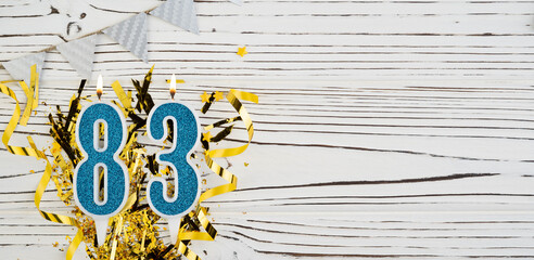 Number 83 blue celebration candle on white wooden background. Happy birthday candles. Concept of...