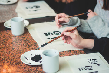 Chinese calligraphy lesson, group of kids learn and practicing traditional calligraphy in class,...