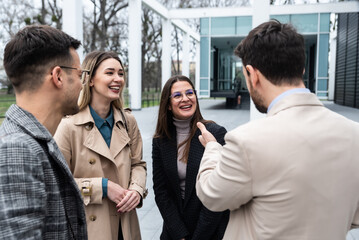 Young businesspeople standing in front of office building talking sharing experience about success business ideas and suggestions improving working conditions of employees and clients