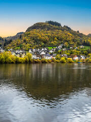 Fototapeta na wymiar Sehl village in foothill of the mountain with colourful trees during autumn and reflection on Moselle river in Cochem-Zell district, Germany