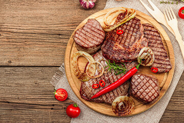 Grilled set of various steaks with vegetables. Ribeye, eye round, flank and striploin steaks