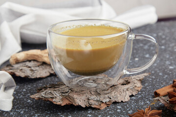 Cup of natural masala tea with spices on tree bark. Healthy traditional indian drink.