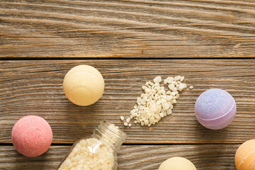 Spa composition with colorful bath bombs and sea salt on a wooden background, top view.