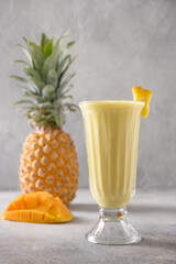 Asian Pineapple and mango lassi, smoothie on gray background. Popular freshness beverage of yogurt,...