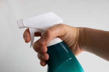 Hand of a white woman holding a spray bottle containing a surface cleaner product